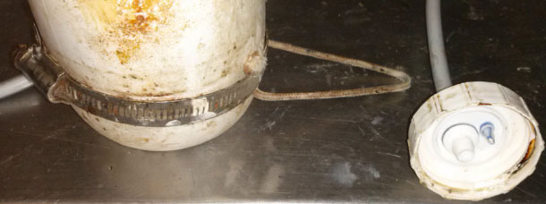 Una corda che passa sotto l\anello di metallo permette posizionare la bottiglia a testa in giù con un piccolo ganciora con un pequeño gancho